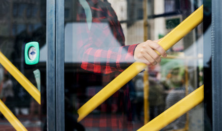 the girl stands near the bus door and holds on to the handrail. traffic safety in public transportの写真素材