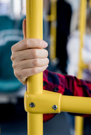 Close-up of hand gripping handrail in public transportation. concept of traffic safetyの写真素材