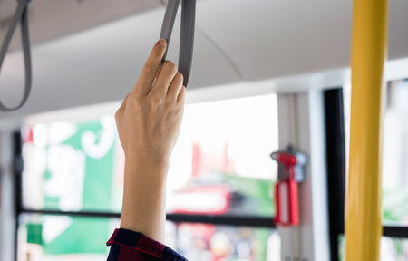 close up of a hand holding a handgrip or handle ring on bus. Safety traveling and a transportation...
