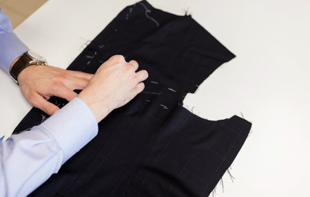 Close-up image of tailor using piece of chalk when drawing detail of jacket on fabricの写真素材