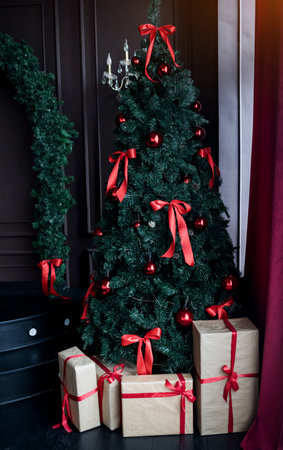 Decorated Christmas tree with gifts in a dark apartmentの写真素材