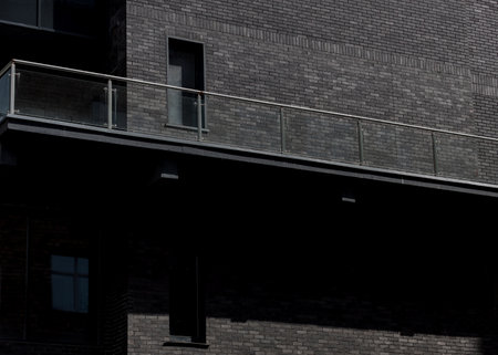 Modern dark gray brick building facade with modern glass balcony detailの写真素材