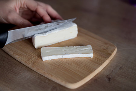 Cutting fresh brie on a wooden board. healthy lifestyleの写真素材