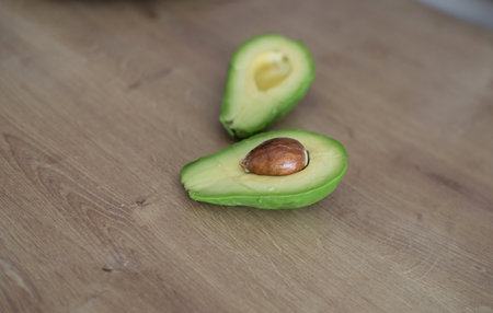 Half a fresh avocado on a wooden table. fruit ideal for culinaryの写真素材