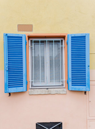 blue window with open blue shutters stands against a bright exterior wallの写真素材