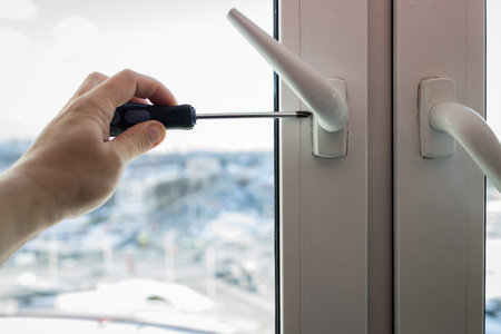 handyman adjusting white pvc plastic window indoors. worker installs windowsの写真素材