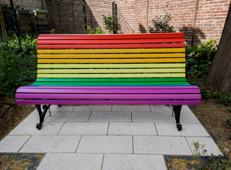 Brightly colored bench with vibrant rainbow stripes, showcasing creativity and public art in urban settingの写真素材