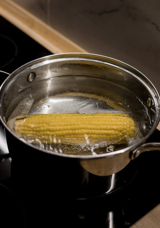Fresh sweet corn cobs in a saucepan in the water on the stove.の写真素材
