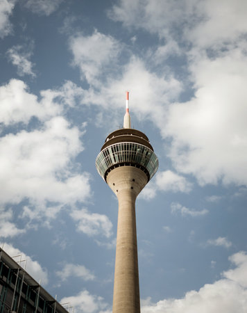 Low angle view of Rheinturm tower standing against cloudy skyの写真素材