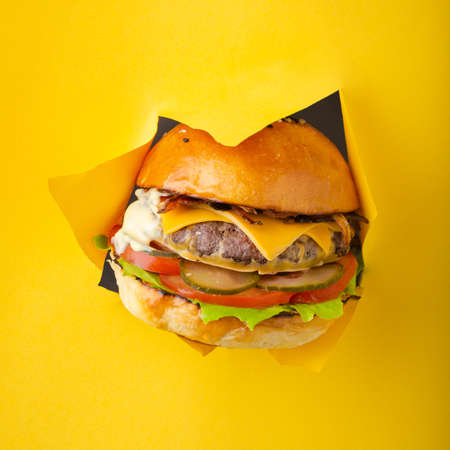 Delicious cheeseburger coming out of yellow colored backgroundの写真素材