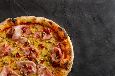 Ham pizza prepared in a wood-fired oven, black background. Flat viewの写真素材