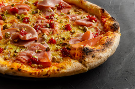 Ham pizza prepared in a wood-fired oven, black background. Closed up.の写真素材