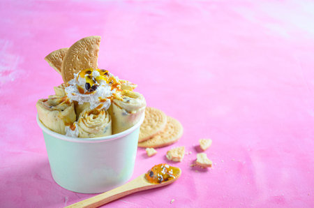 Parchita pie ice cream roll, with chantilly cream, passion fruit syrup, on a pink backgroundの写真素材