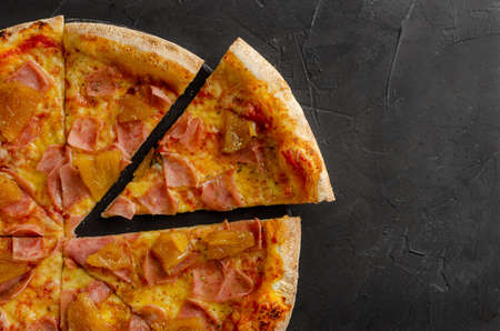 Flat viewHawaiian pizza prepared in a wood-fired oven. Black background. Flat view and slice.の写真素材