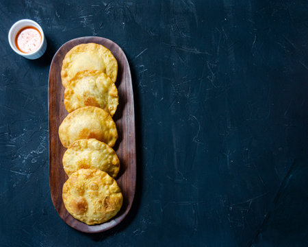 Girl's hands with empanada typical food from Venezuela adding gasacaca sauce, trio sauce, woodwn tableの写真素材