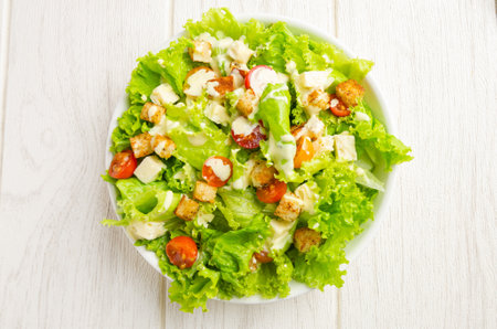 Lettuce, tomato and cheese salad, croutons, dressing. White background.の写真素材