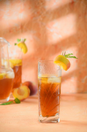 peach iced tea Jug in the background. Shadows on a melon-colored background.の写真素材