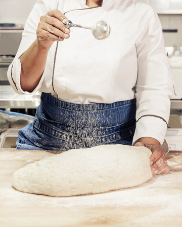 Kneading and preparation of sourdough-based bread. On a wooden table. in bakeryの写真素材