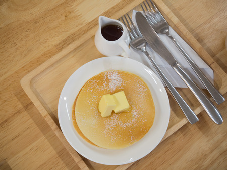 Pancakes on a white dish  with a small jug of syrup, serve on the wooden plateの写真素材