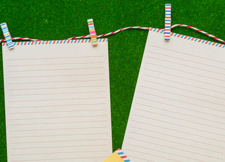 Two letter papers with colorful clips on green backgroundの写真素材