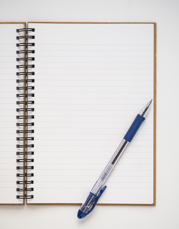 A blank lined notebook with blue pen on white backgroundの写真素材