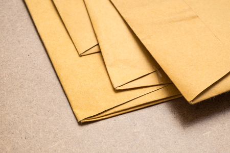 Stack of used brown envelopes on brown backgroundの写真素材
