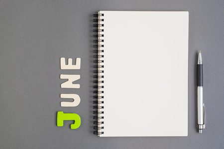 Spiral open notebook with pen and June month wording on grey backgroundの写真素材