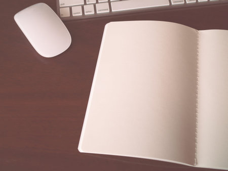 Open notebook with mouse and keyboard on wood background - vintage filter tone