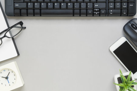 Desk above, table top view of office desk with notebook, pen, clock, keyboard and mouse on grey...