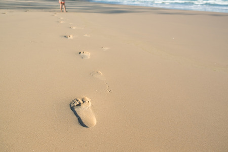 A kid walking on the beach leaving footprints in the sandの写真素材