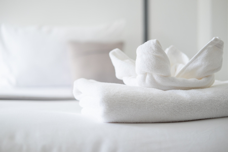 Close up on white fresh towel on bed in bedroom in the hotelの写真素材