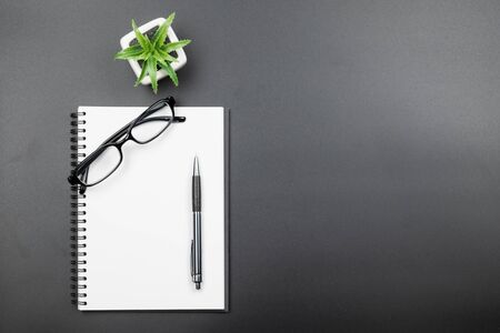 Table top view of empty blank page notebook with pen and eyeglasses on black backgroundの写真素材