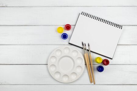 Top view of a blank art book with water color and paintbrush on white wooden backgroundの写真素材