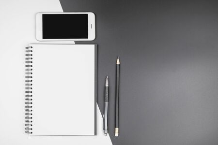Top view of minimal office desk with an empty open notebook, pen, pencil, mobile phone and eyeglassesの写真素材