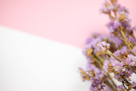 Selective focus on purple statice flower bouquet on pastel pink and white background
