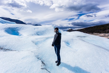 Man standing drinking whiskey on Glacier, black clothing, smilinの写真素材
