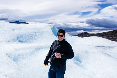 Man standing drinking whiskey on Glacier, black clothing, smilinの写真素材