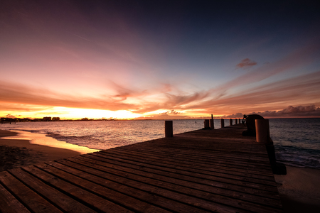 Wooden pier on the sea during sunset. Beautiful orange purple skies reflecting on the ocean. Grace Bay Beach, Providenciales, Turks and Caicos.の写真素材
