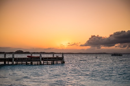 Wooden pier on the sea during sunset. Beautiful orange purple skies reflecting on the ocean. Grace Bay Beach, Providenciales, Turks and Caicos.の写真素材