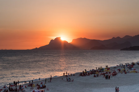 Orange sunset by the ocean in Piratininga, Niteri, with sun dipping behing the Gavea Stone in Rio de...