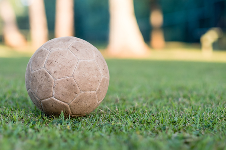 vintage used soccer ball lying on the grass in park, in the shadow. Trees in the background are in the sun, Rio de Janeiroの写真素材