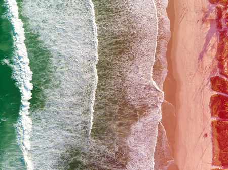 Top view Drone photo of beach in Barra da Tijuca, Rio de Janeiro, Brazil. Waves crashing with whitewash, the golden sand and the boardwalk beaches can be seen. Colored Light leak filter appliedの写真素材