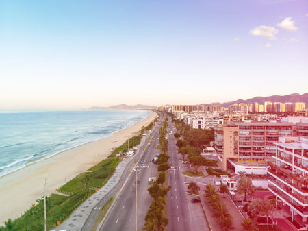 Drone photo of sunrise in Barra da Tijuca beach and boardwalk, beachfront buildings catching the...