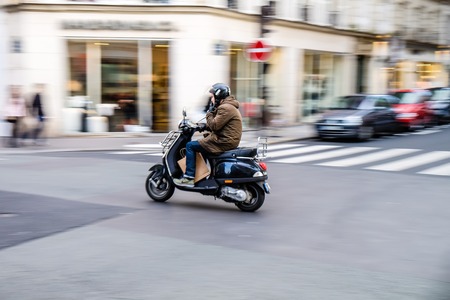 Paris, France - May 2, 2014 : Man comutes throught Paris with scooter while smoking, motion blur effect shows only rider in focusのeditorial素材