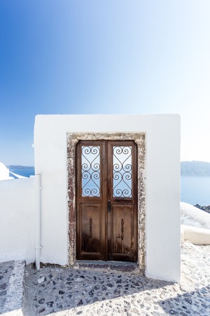 Wooden door on white portal, leading as the entrance to a hotel in Oia, Santorini Greece. Copyspaceの写真素材