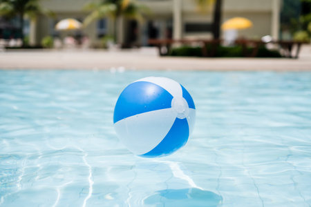 Blue and white inflatable ball floating on swimming pool under the summer sun