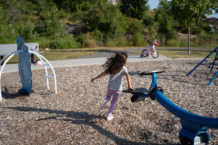 Young girl in pink clothes and running in a park seen from behindの写真素材