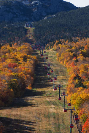 Cable car view. Fall colour seen from above, with telephoto lens, on Stowe Mountains in Vermont, US. A forest of trees turning red and orange.の写真素材
