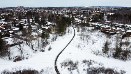 Aerial top view of a foot path in winter , surrounded by snow. Kanata neighborhood can be seen in the background. Ottawa, Ontario, Canadaの写真素材