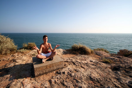 sexy man doing yoga on the coastの写真素材